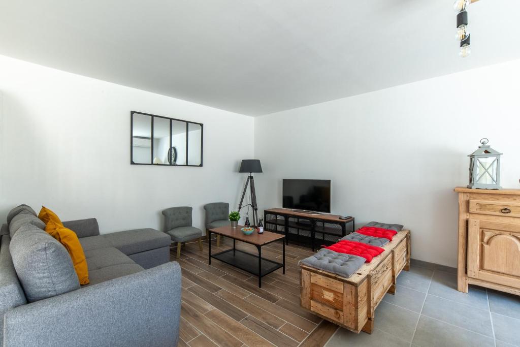 a living room with a couch and a table at Gîte du Tilleul - Maison climatisée pour 8 voyageurs in Houesville