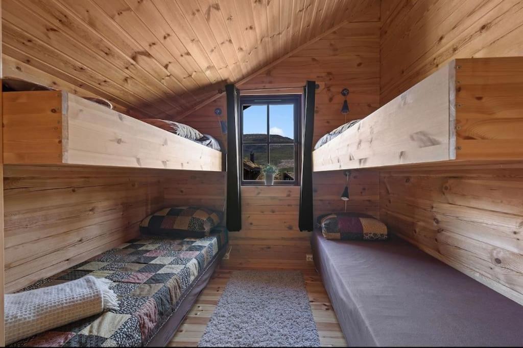 two bunk beds in a log cabin with a window at Tradisjonell laftet hytte in Vradal