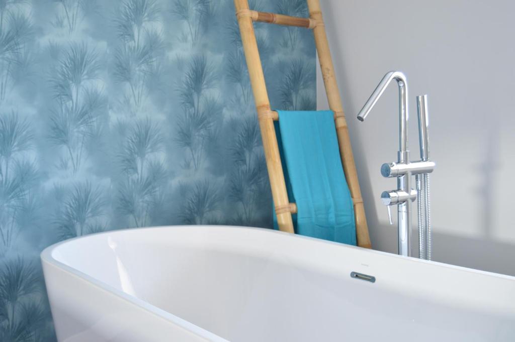 baño con bañera blanca y papel pintado azul en O Cabanel de Ali, en Muxía