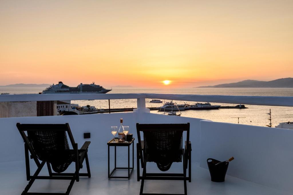a balcony with a view of a cruise ship at sunset at She Mykonos - The Residency in Mýkonos City