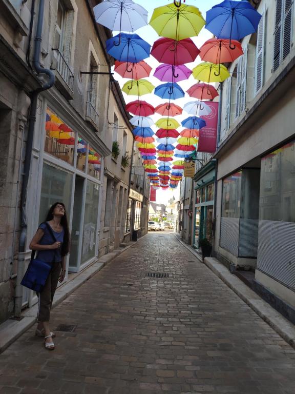 een vrouw die over een straat loopt onder paraplu's bij Location maison de vacances Sancerre in Sancerre