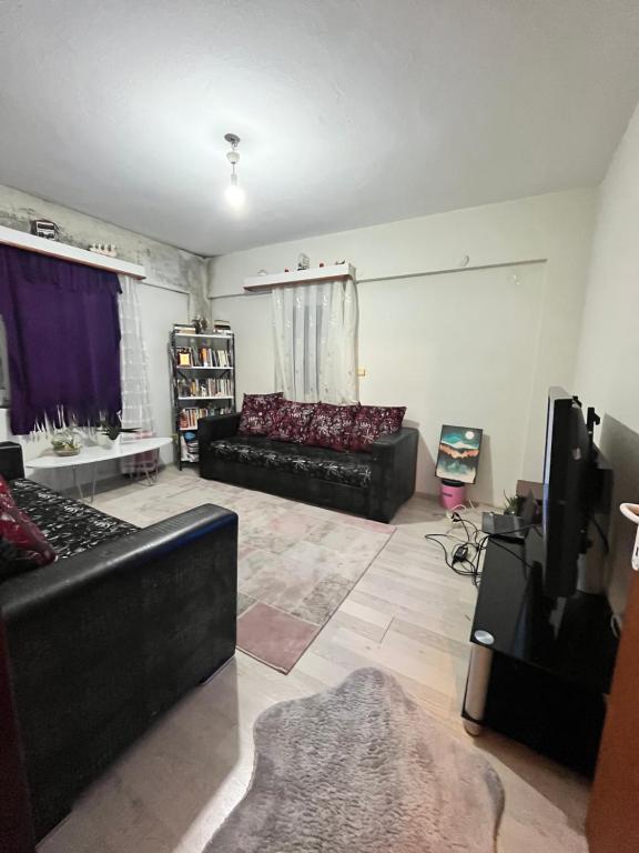 sala de estar con sofá negro y TV en Huzurlu eviniz, en Golbası