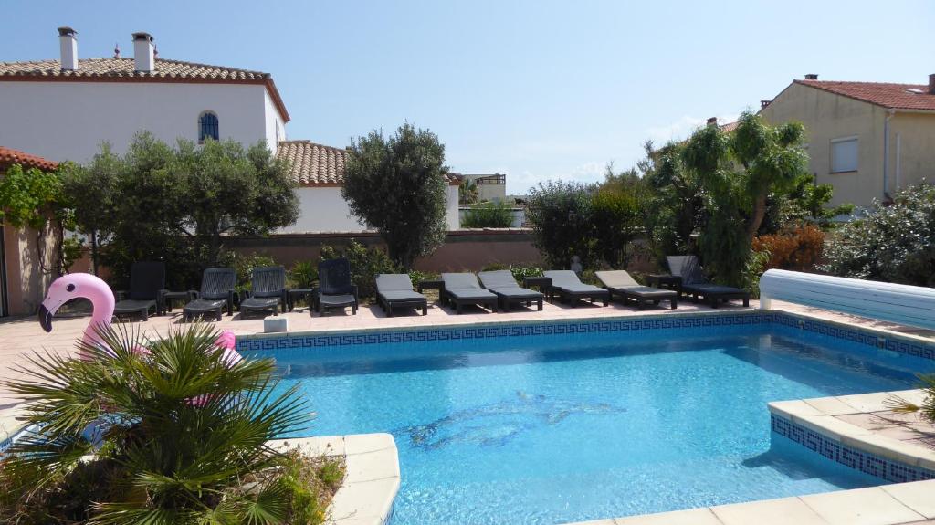 a swimming pool with a pink swan in a yard at les 2 dauphins in Le Barcarès