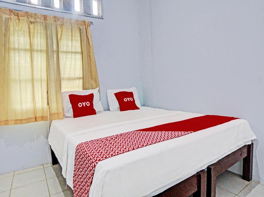 un letto in una camera con due cuscini rossi sopra di OYO 92429 Vania Guest House a Medan