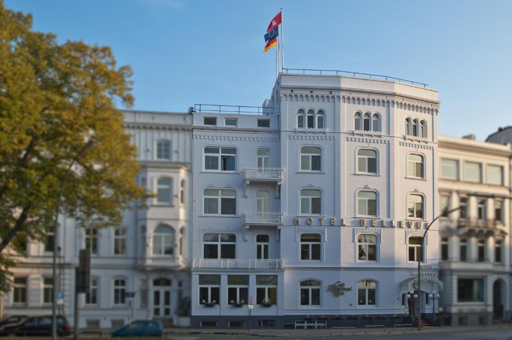 a white building with a flag on top of it at Relexa Hotel Bellevue an der Alster in Hamburg