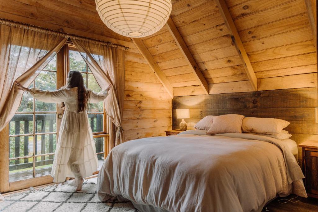 Una donna sta in una camera da letto che guarda fuori dalla finestra di The Quarters a Strahan