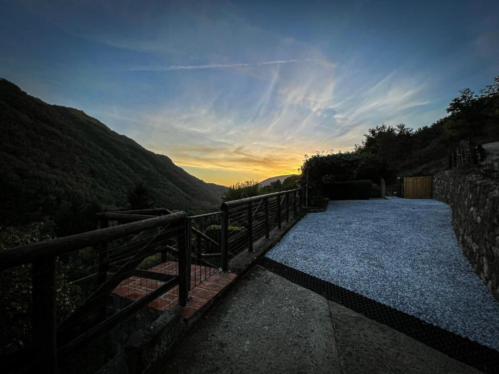 a pathway with a fence and a sunset in the mountains at Old Village Linda - Tra Lunigiana & Cinque Terre in Comano