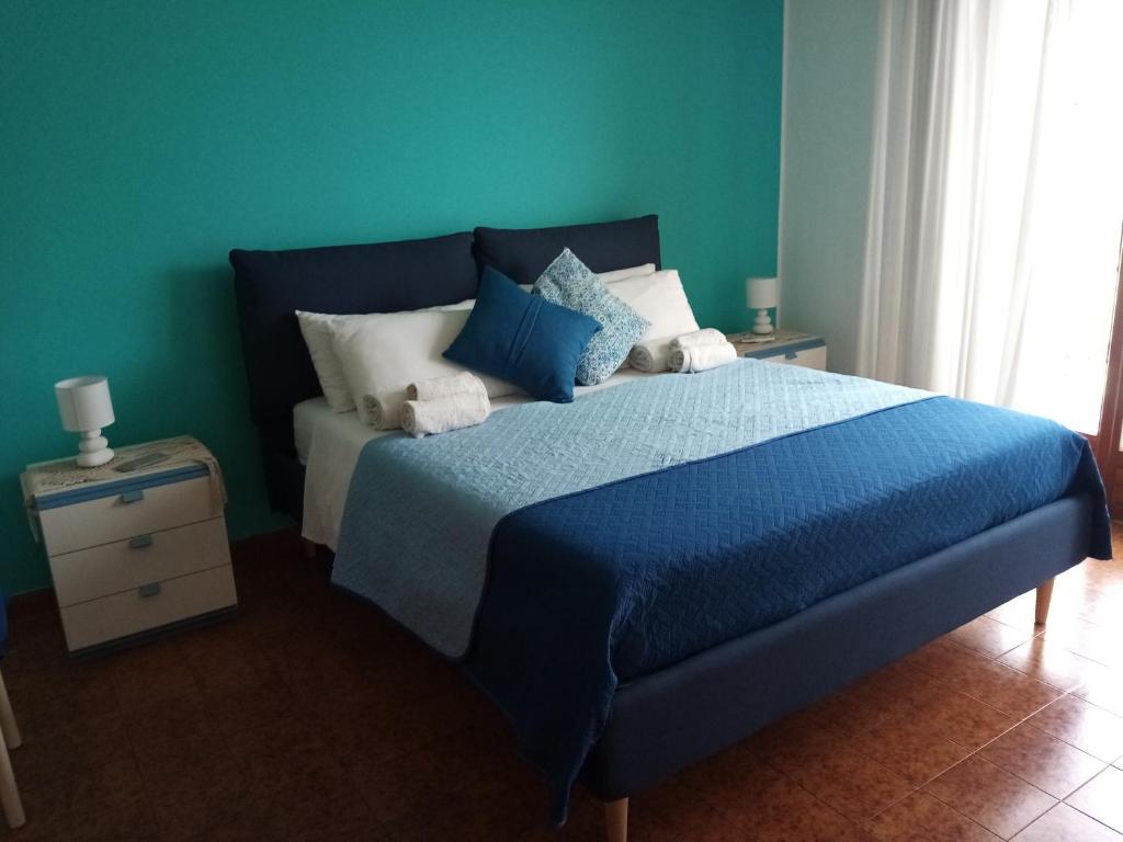 ein blaues Schlafzimmer mit einem Bett mit blauen Laken und Kissen in der Unterkunft Casa Rosamarina in Mondello