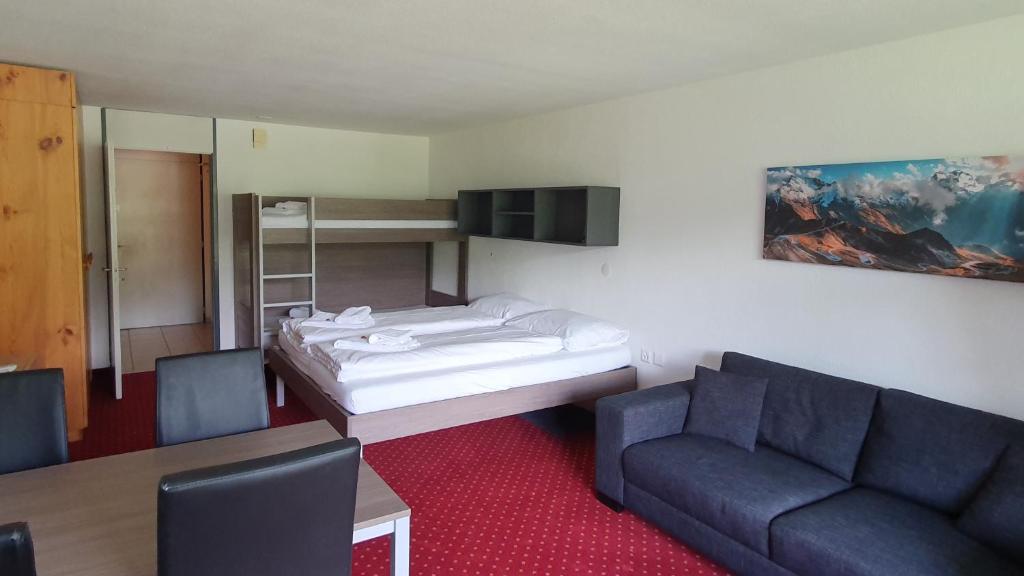 um quarto com uma cama, um sofá e uma mesa em Apart Holidays - Haus Acletta em Disentis