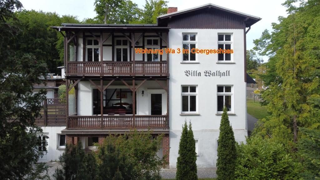 a white house with a balcony on the side of it at Sonnige-Ferienwohnung-100qm-im-1-Obergeschoss-der-Villa-Walhall-in-einem-parkaehnlichen-Garten in Ostseebad Sellin