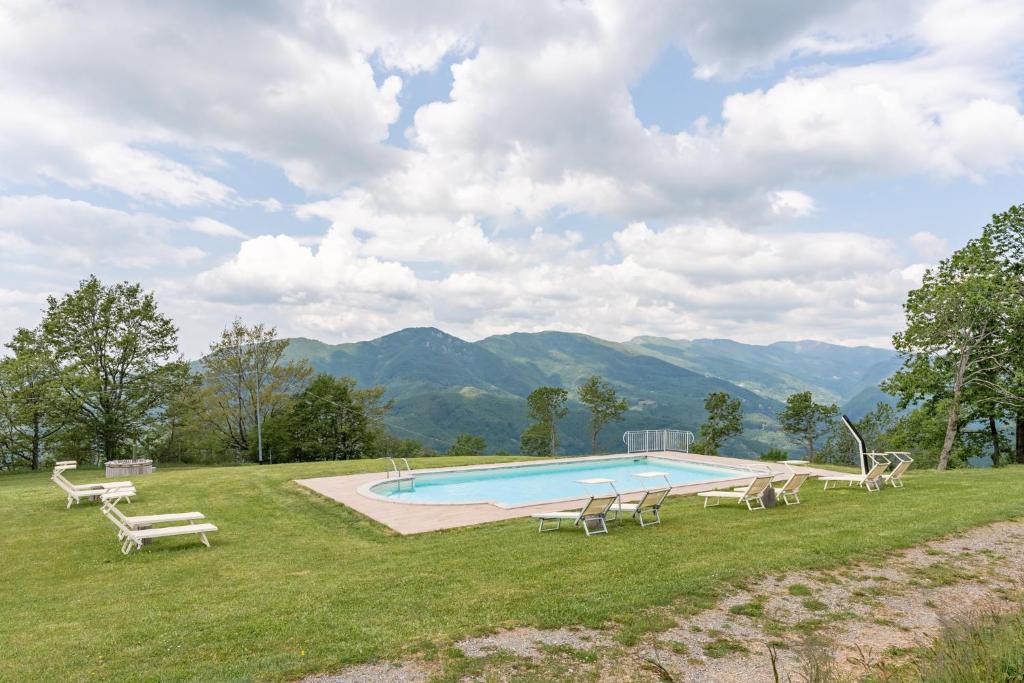 a swimming pool in a field with chairs around it at Il Serrino Family tra le montagne in Pistoia