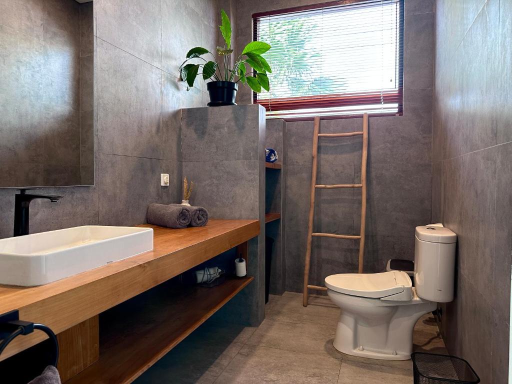 uma casa de banho com um lavatório, um WC e um espelho. em LINDT - Bali Invest Club em Dalung