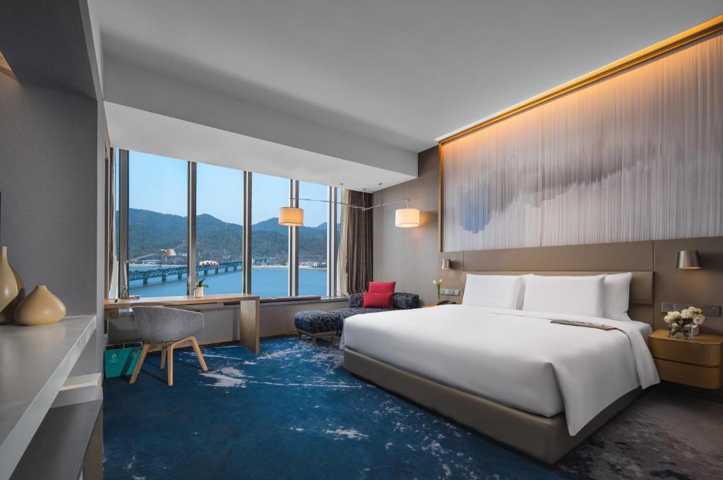 杭州市にあるLe Meridien Hangzhou, Binjiangのベッドと大きな窓が備わるホテルルームです。