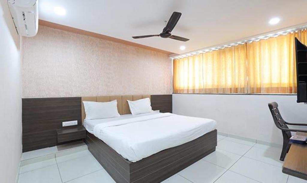 1 dormitorio con cama, silla y escritorio en FabHotel The Heaven en Ahmedabad