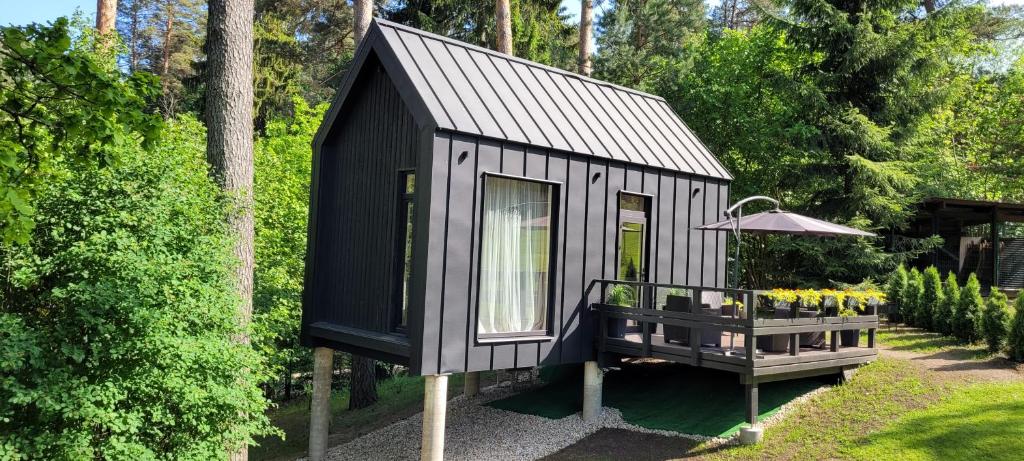 ein schwarzes winziges Haus mit einem Tisch und einem Regenschirm in der Unterkunft Pine Nook in Ogre