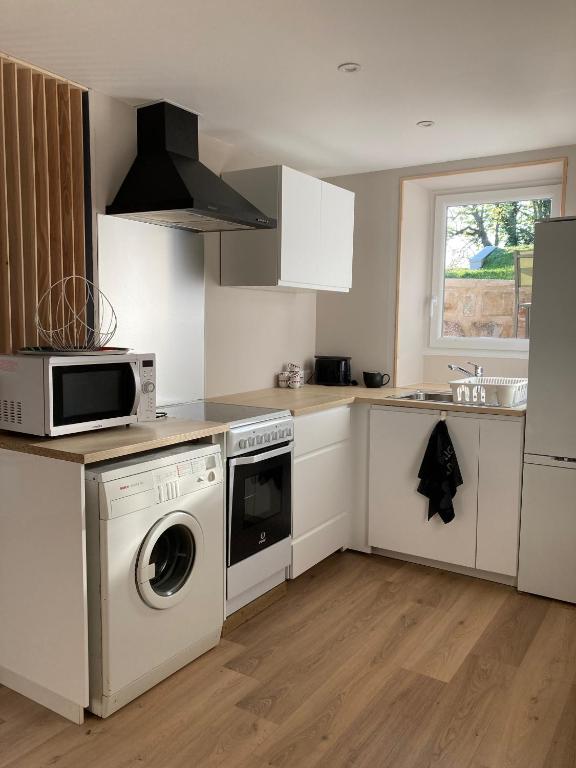 a kitchen with a washing machine and a microwave at Le Clos des Grands Frênes in Pons