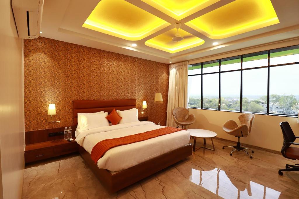 ein Hotelzimmer mit einem Bett, einem Tisch und Stühlen in der Unterkunft Four Petals Executive by LHMS in Akalkot