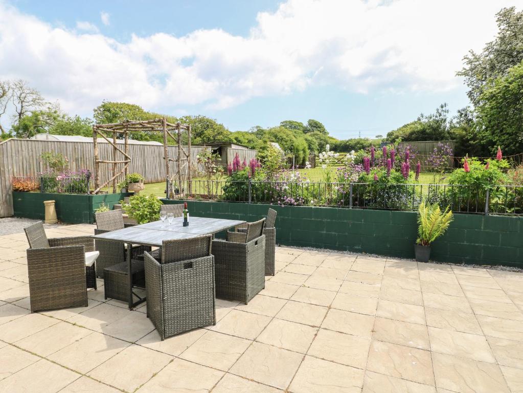 a patio with a table and chairs in a garden at Nash Lodge in Pembroke Dock