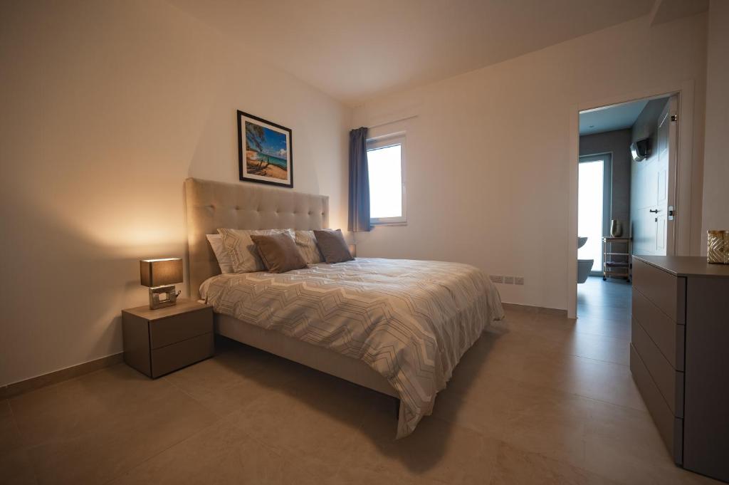 a bedroom with a large bed and a window at The Address Seafront Suites with Hot Tub in Pieta