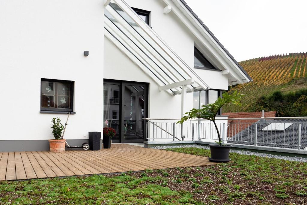 a white house with a wooden deck in the yard at Ferienwohnung Epting in Kappelrodeck