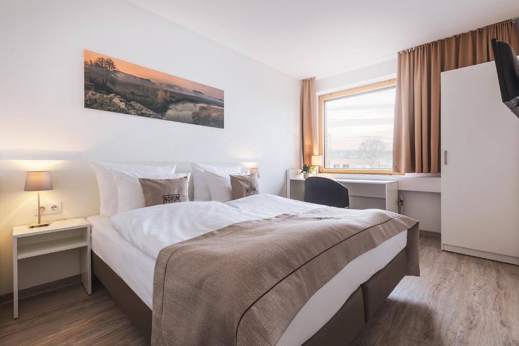 um quarto de hotel com uma cama grande e uma janela em Novum Akademiehotel Kiel em Kiel