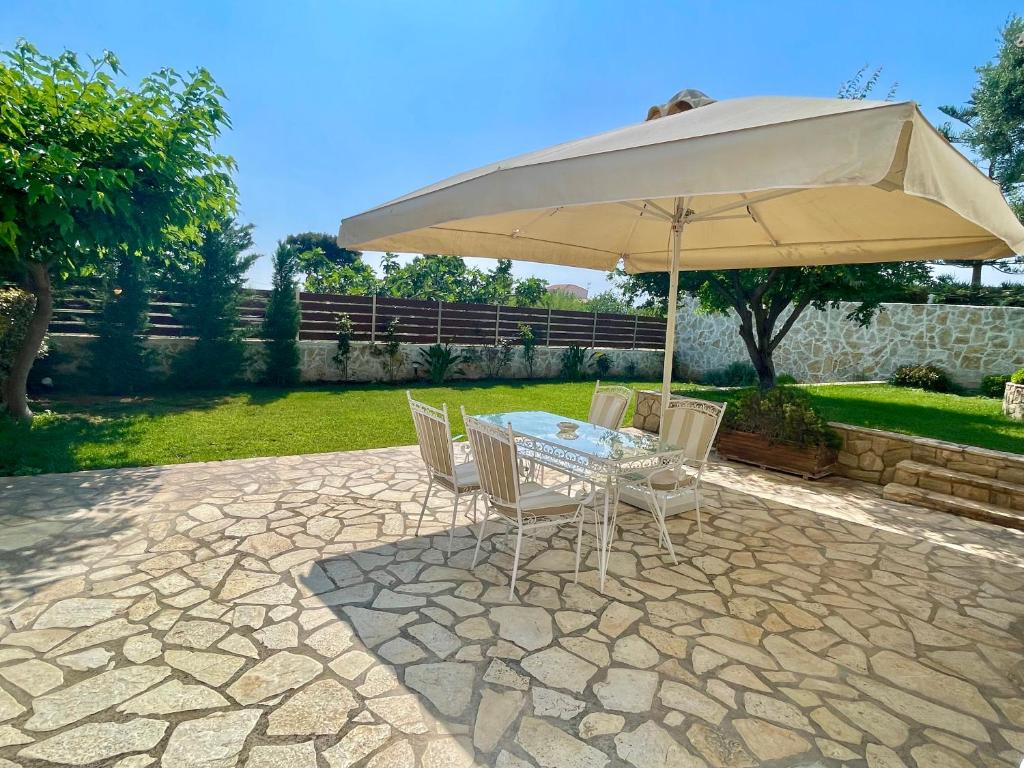 einen Tisch und Stühle unter einem Sonnenschirm auf einer Terrasse in der Unterkunft Apartment near airport and beach in Artemida