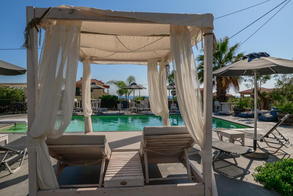 a gazebo with chairs and an umbrella next to a pool at Evita Studios in Svoronata
