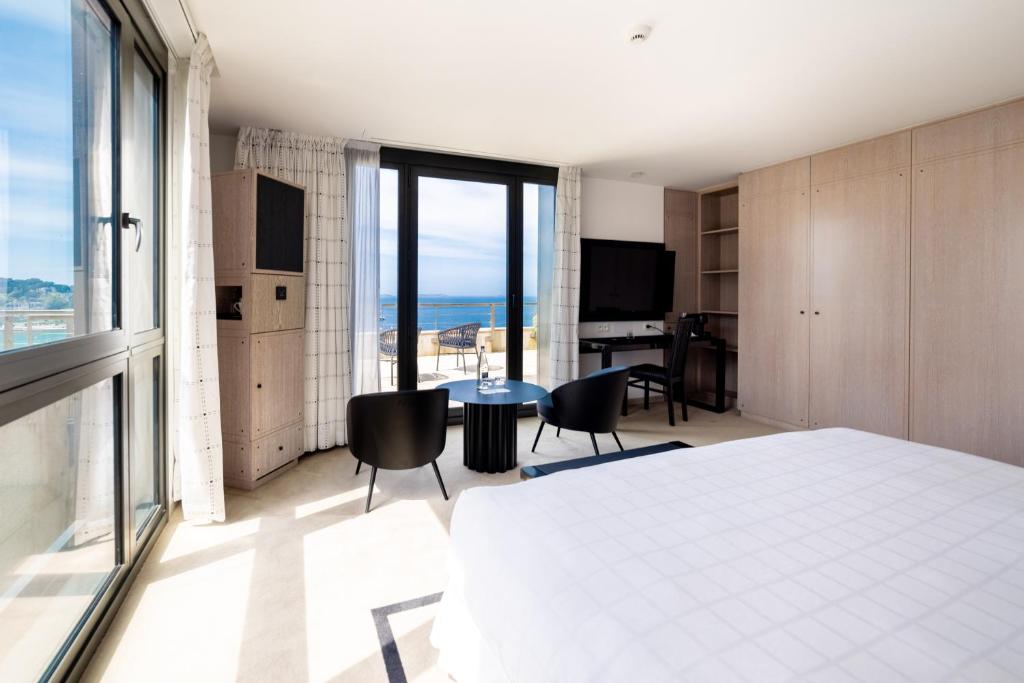 a bedroom with a bed and a table and chairs at L'Agapa Hôtel - Spa Codage in Perros-Guirec