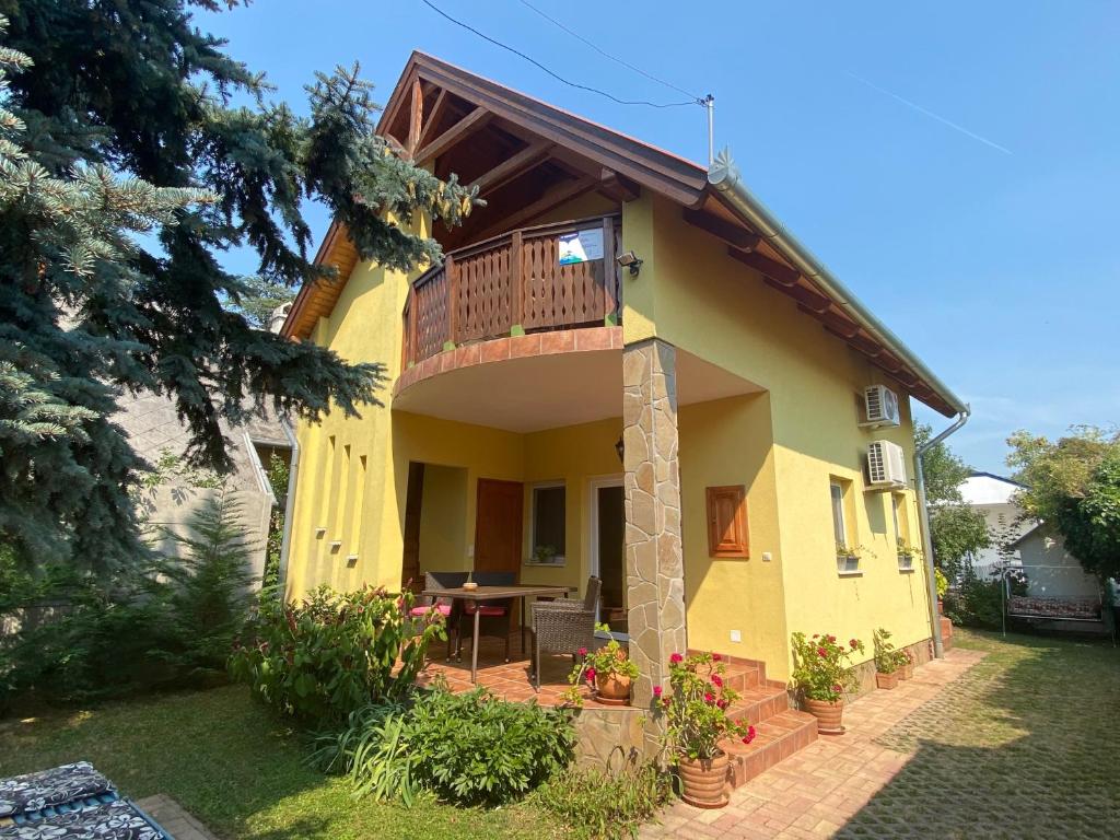 Casa amarilla con balcón y mesa en Villa Elisa en Vonyarcvashegy