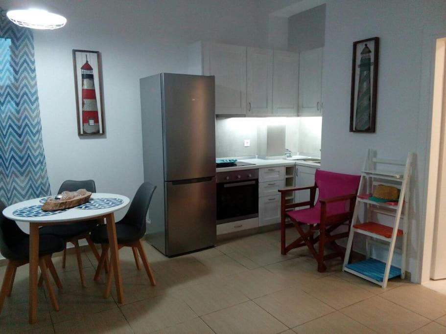 a kitchen with a refrigerator and a table and chairs at Vourkari Studio 2 with kitchen in Ioulis