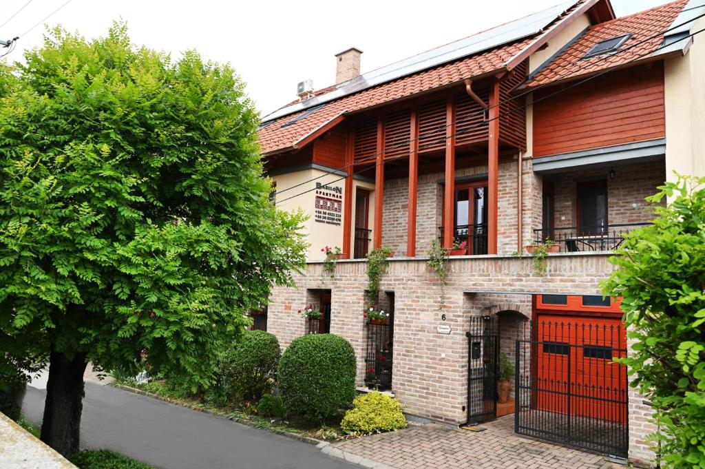 a brick building with a red door on a street at Babilon Gyula Szállás De Luxe in Gyula