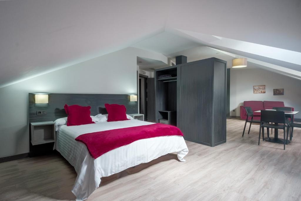 ein Schlafzimmer mit einem großen Bett mit roten Kissen in der Unterkunft Apartamentos Capua in Gijón
