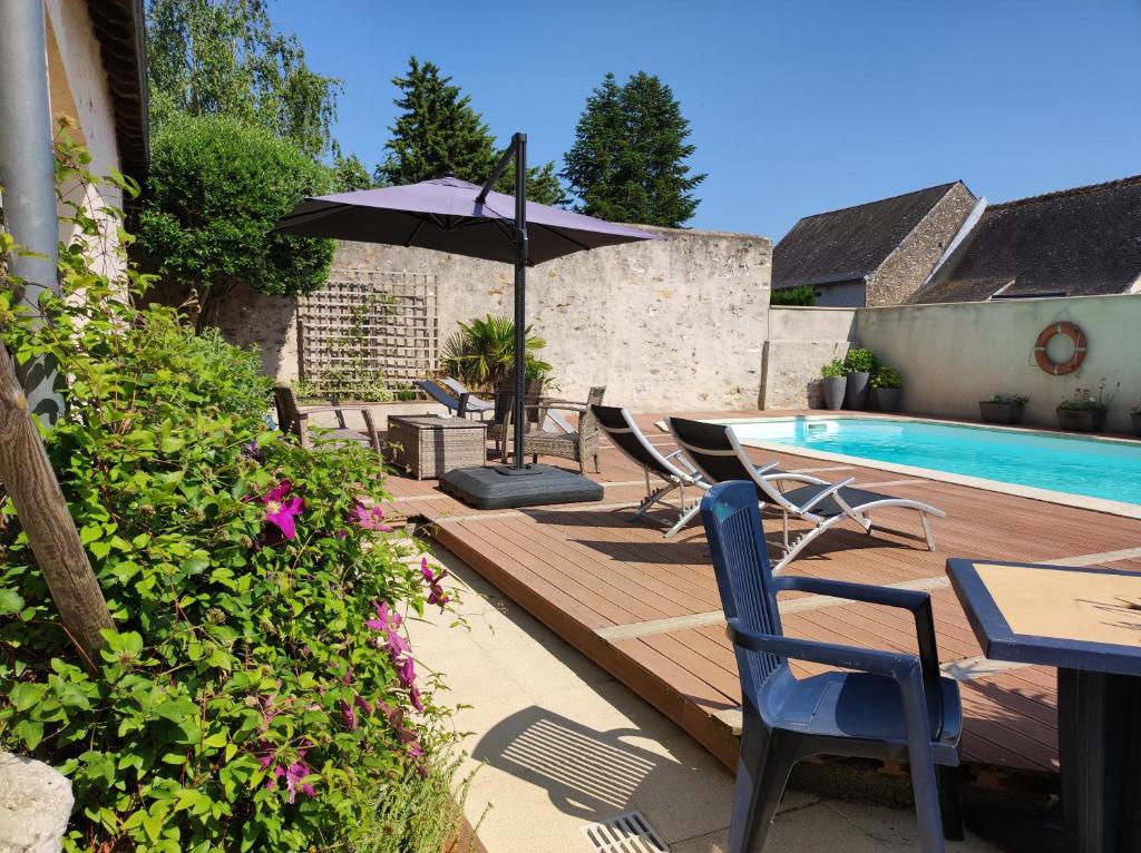 a deck with chairs and an umbrella next to a swimming pool at La Hautée des Francs in Veigné