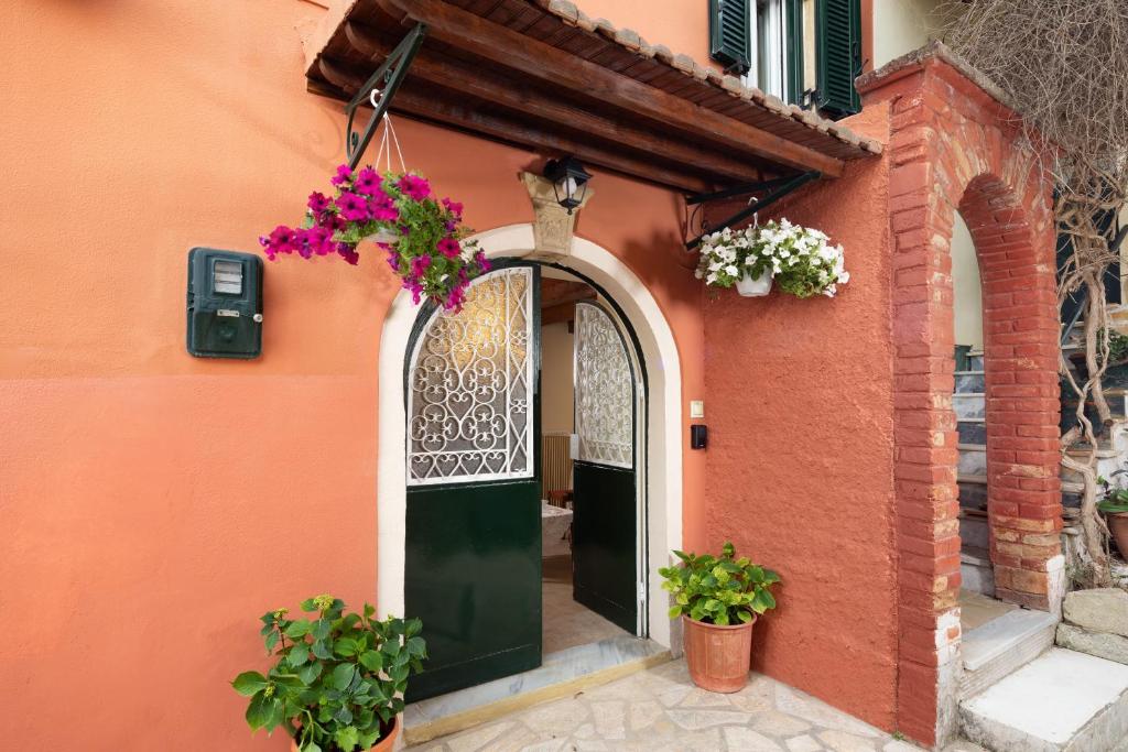 an orange building with a green door and flowers at Lemon Tree House in Kouramádes