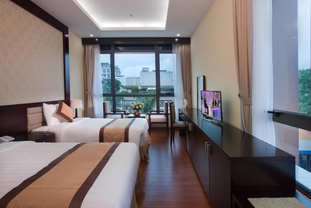 a hotel room with two beds and a balcony at TQT Hotel in Hanoi