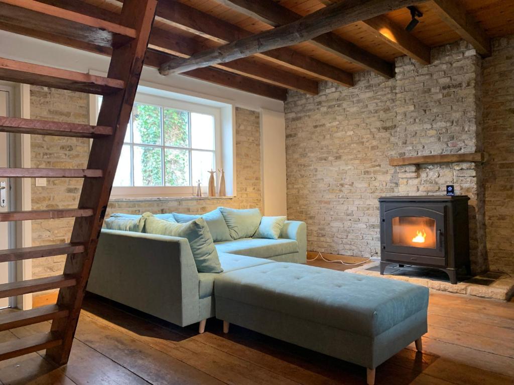 ein Wohnzimmer mit einem Sofa und einem Kamin in der Unterkunft De Scheure, charmant vakantiehuisje midden in de natuur in Alveringem