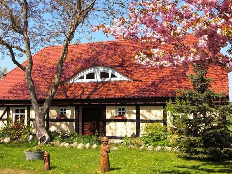 a house with a red roof with a statue in the yard at Ruegen Fewo 119 in Groß Schoritz