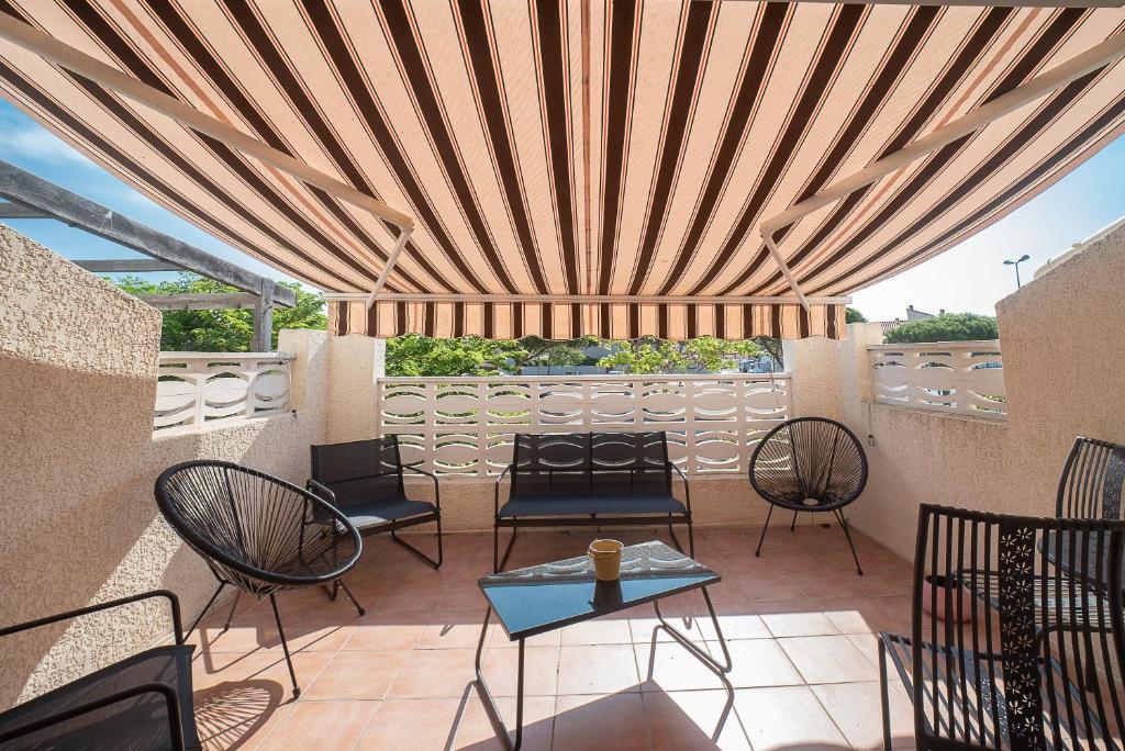 eine Terrasse mit Stühlen und Tischen unter einer Holzdecke in der Unterkunft Une Maison à la Mer - Proche de la marina in Saint-Cyprien
