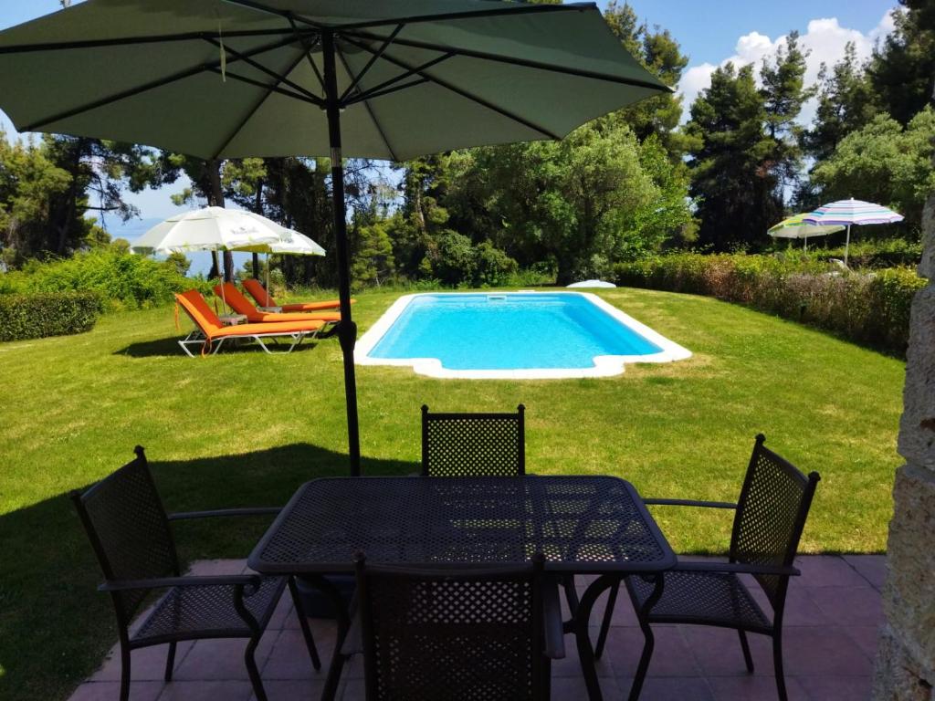 克里皮吉的住宿－Stone Made Private Pool Villas Kriopigi，桌椅、遮阳伞和游泳池