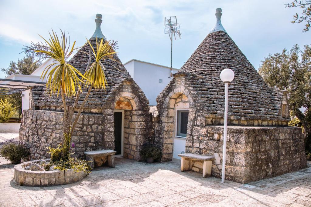a stone house with two towers with a palm tree at Il TrullOzio in Castellana Grotte