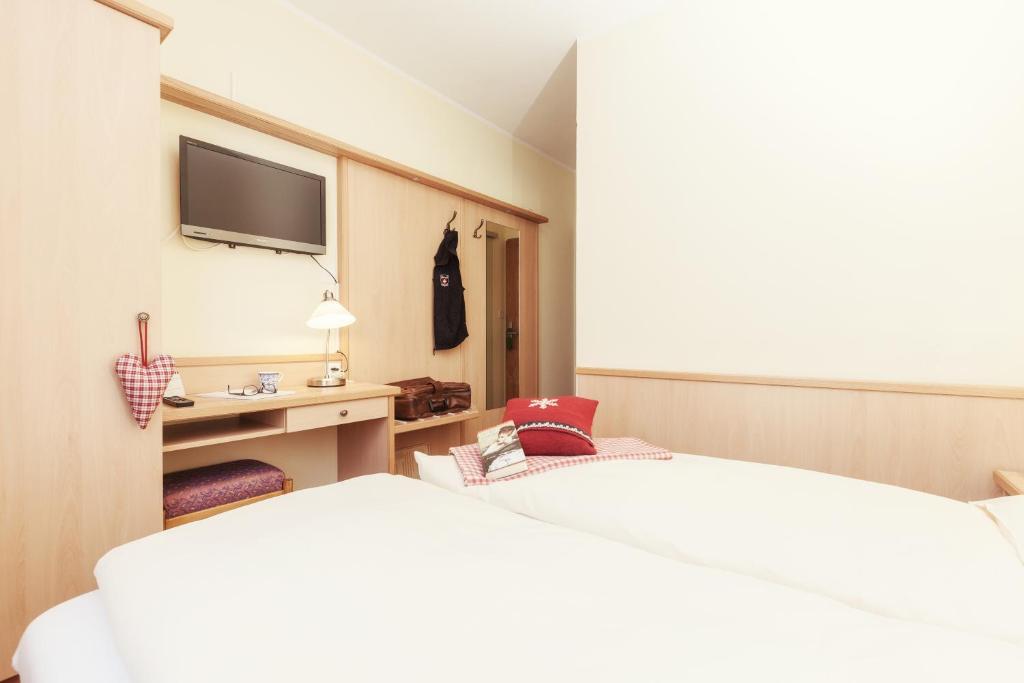 a hotel room with a bed and a tv at Le Petit CHARME-INN in Zermatt