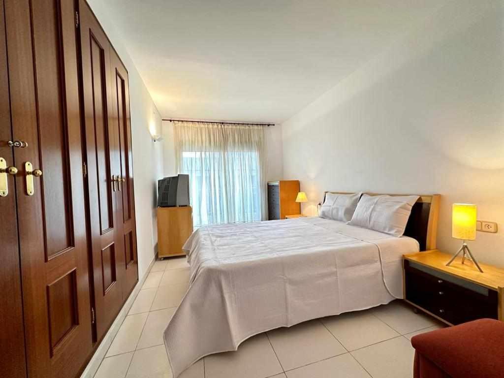 une chambre avec un grand lit blanc et une télévision dans l'établissement Tossa de Mar Veran, parking Wifi, 100m de la playa, à Tossa de Mar