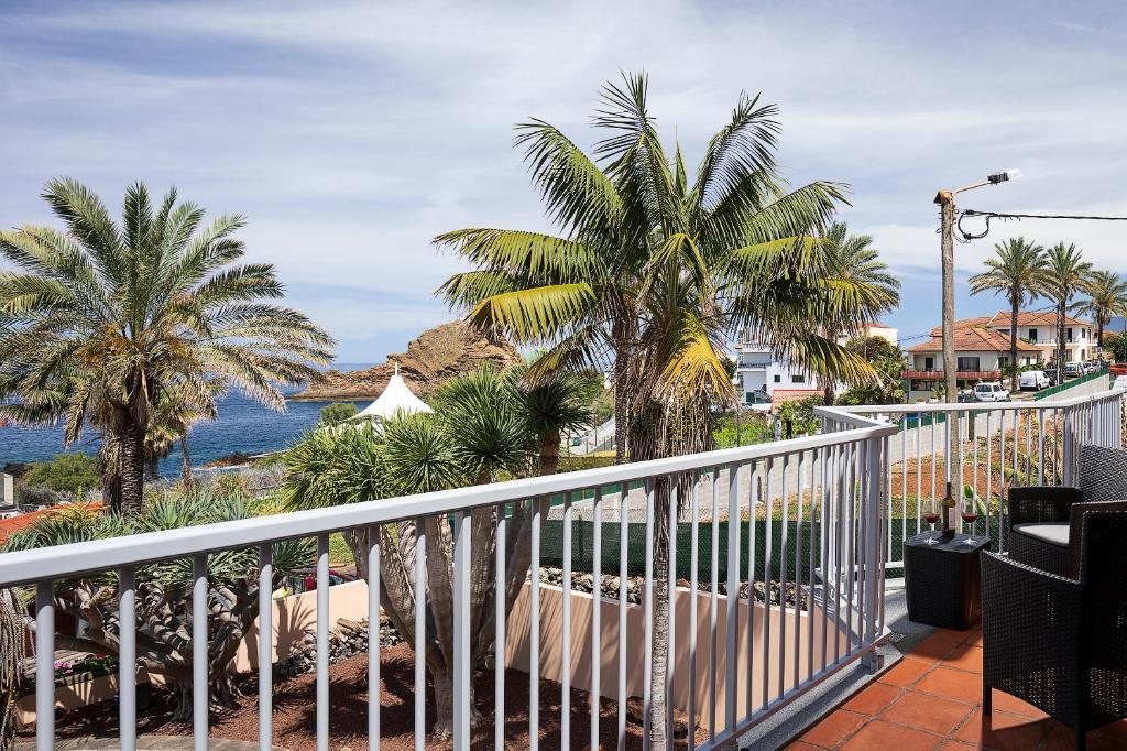 a balcony with a view of the ocean and palm trees at Porto Moniz Villa in Porto Moniz