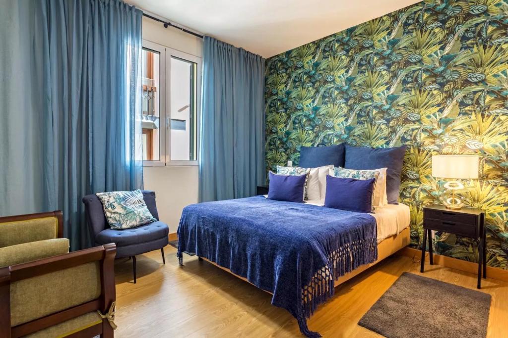 - une chambre avec un lit bleu et une chaise dans l'établissement Apartamentos da Sé Catedral, à Funchal