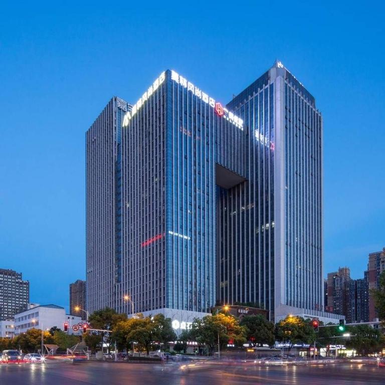 een groot hoog gebouw in een stad 's nachts bij Morninginn, Ma Wangdui Wanjiali Metro Station in Changsha