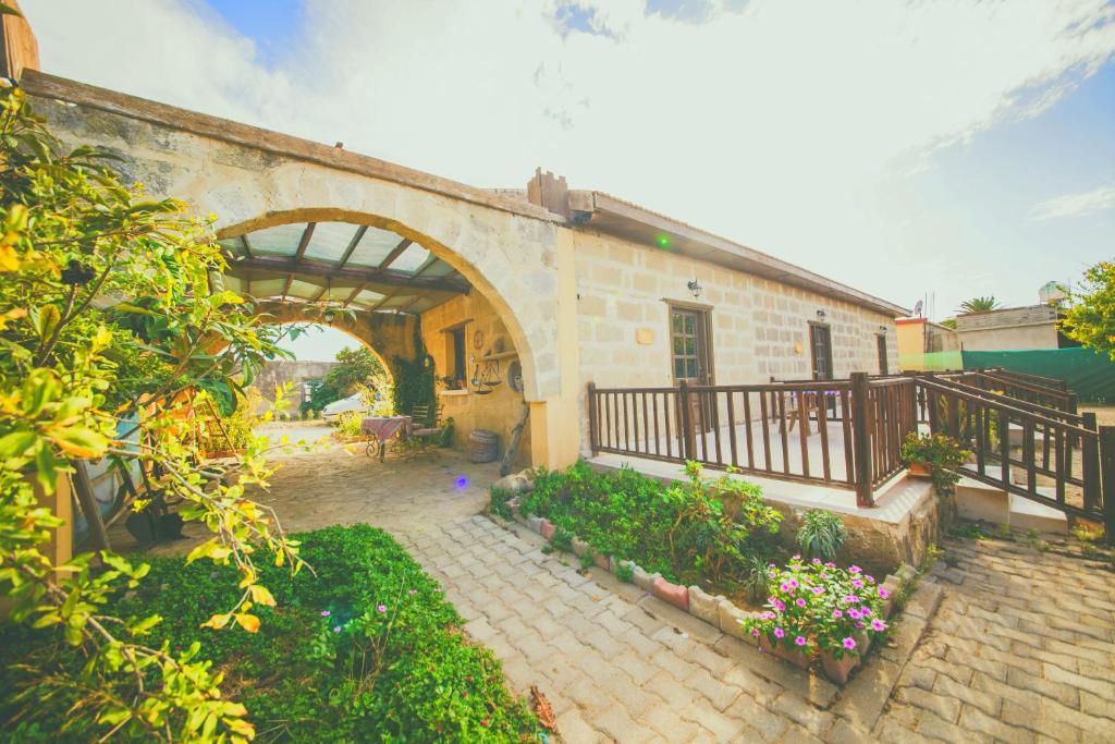 a building with an arch and a patio with flowers at CASTLE KARPASIA Guest House in Rizokarpaso