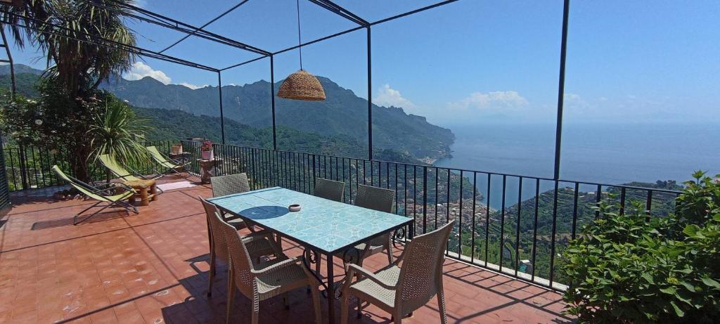 einen Tisch und Stühle auf einem Balkon mit Aussicht in der Unterkunft PinkSunsetRavello in Ravello
