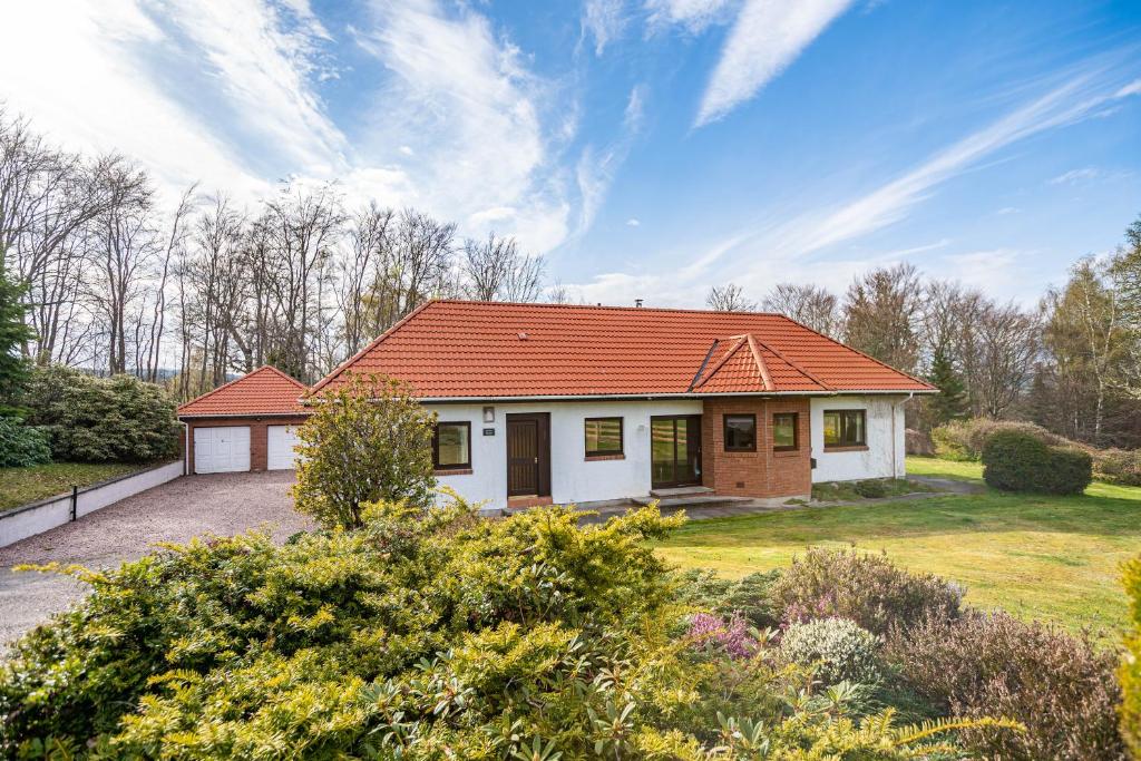 a house with an orange roof on a yard at Corrie House with Hot Tub in Belladrum