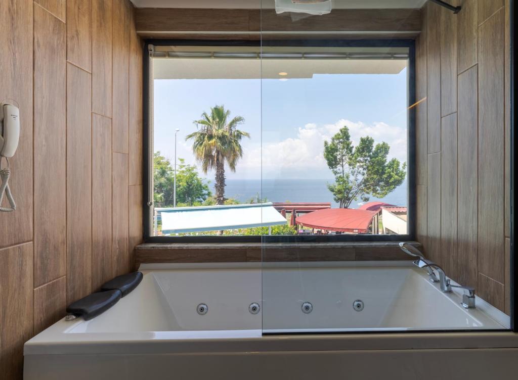 a bath tub in a bathroom with a large window at Tema 242 Hotel in Antalya