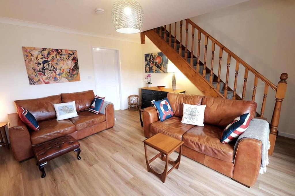 a living room with two leather couches and a staircase at Lovely two bed home in Cemaes, Anglesey in Cemaes Bay